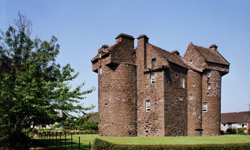 The red stoned Claypotts Castle with its striking circular towers and asymetric layout.