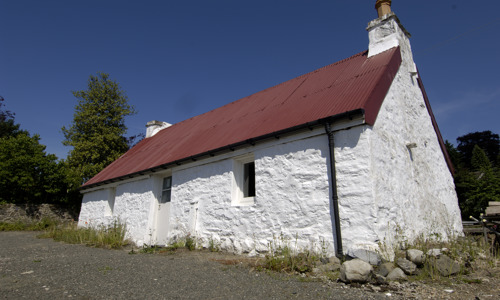 A white cottage with two chimneys and a red roof