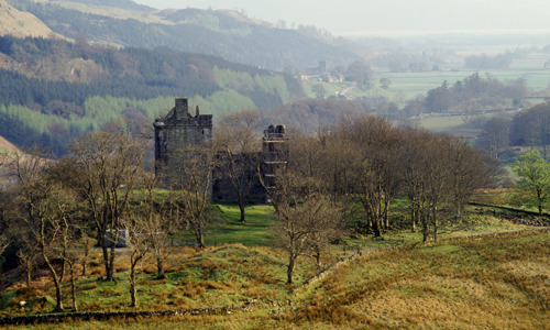 Carnasserie Castle seen from a distance, surrounded by an autumn landscape.