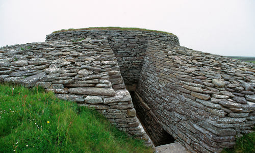 A passage made by stone walls leading down into the chambered cairn.