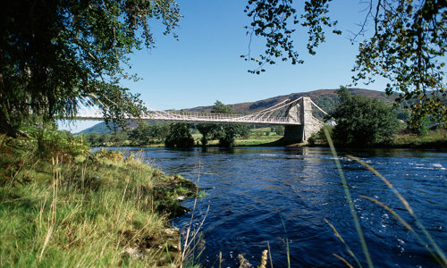 A white and grey suspension bridge spanning the river Oich.