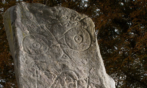 A light stone covered in carvings that include circles and spirals.