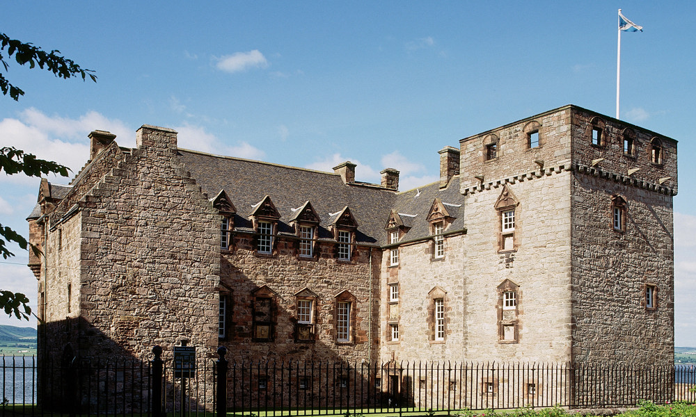 A photograph of a large house with a square tower, flying a Saltire flag.