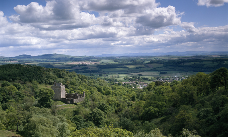A distant view of Castle Campbell, showing the surrounding woodland and countryside.