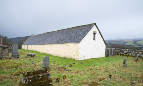 A white cottage-style church with a graveyard in front of it