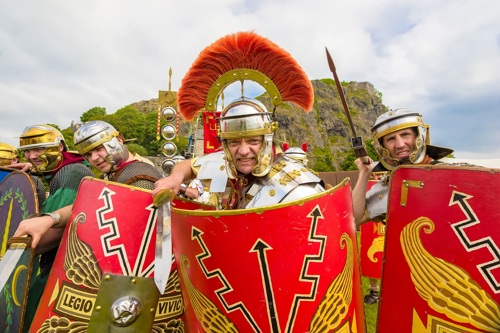 Reenactors dressed as Romans brandish swords and spears and shields