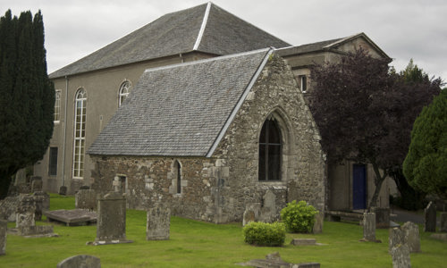 A church with trees and gravestones in the foreground