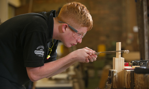 A person in a workshop making something out of wood