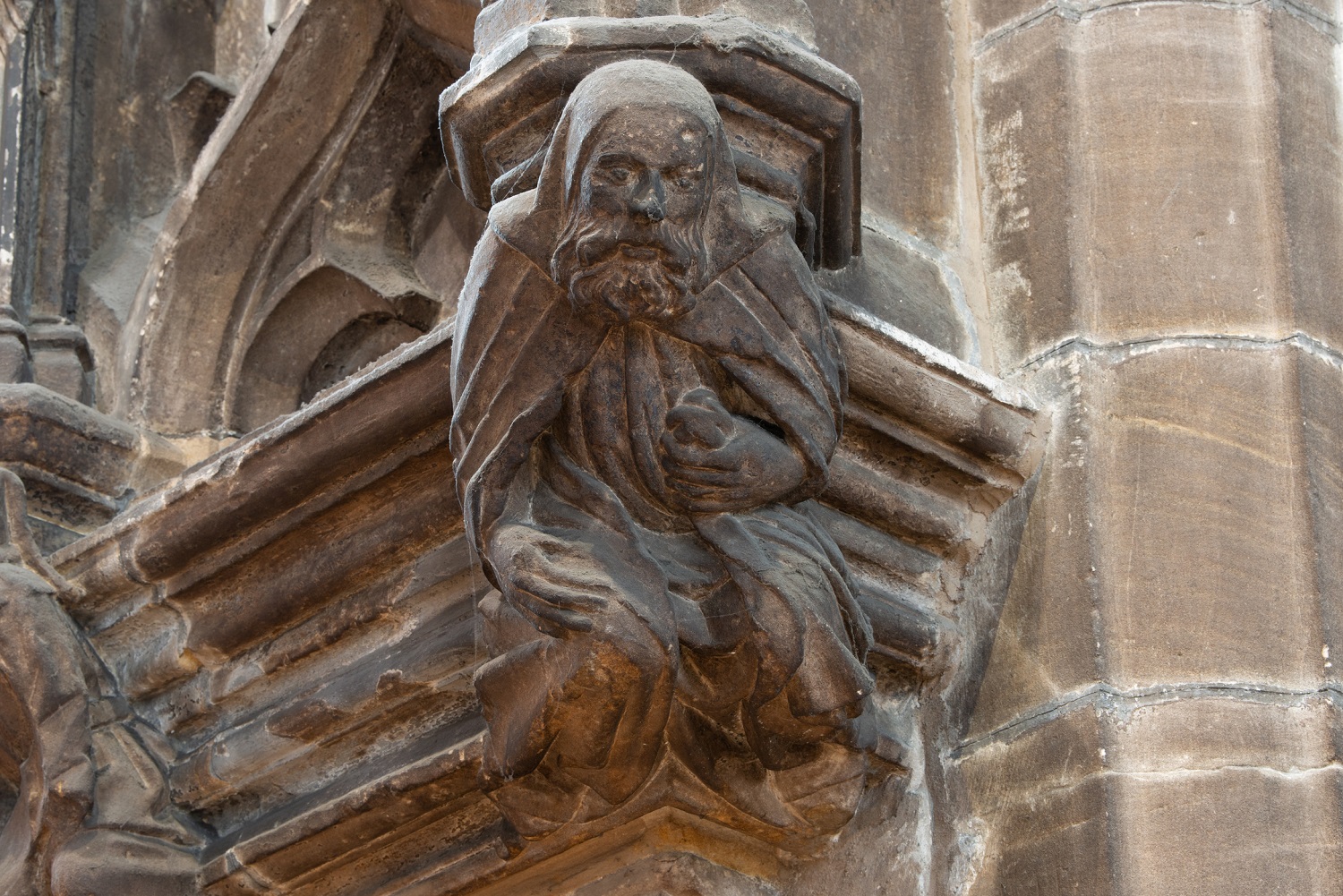 Stone carving of a robed and bearded figure at Glasgow Cathedral, positioned beneath an ornate architectural canopy.