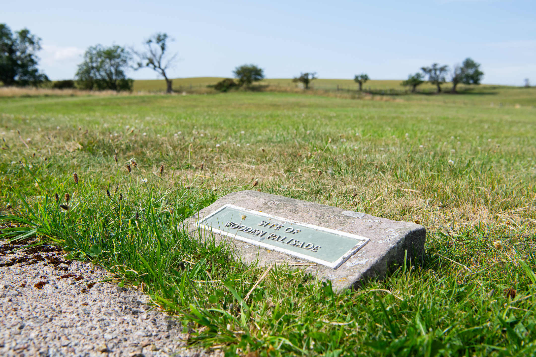 Sign on stone panel in grassy area that reads: SITE OF WOODEN PALISADE