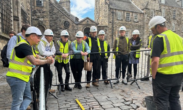 A group in hard hats and hi vis jackets at Stirling Castle learn about traditional skills 
