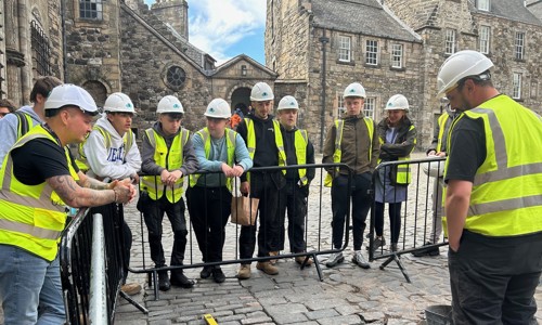 A group in hard hats and hi vis jackets at Stirling Castle learn about traditional skills 