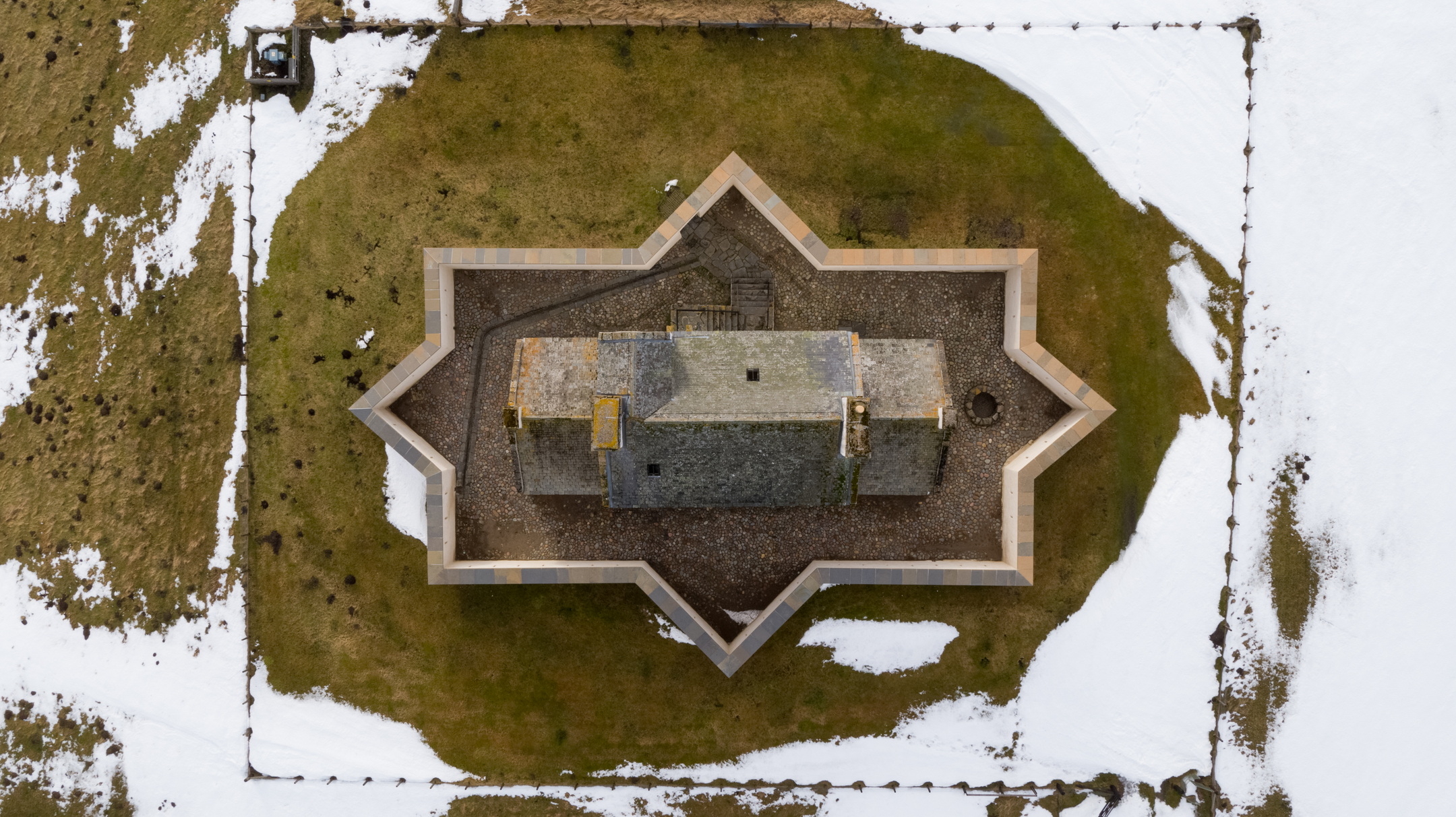 Aerial top-down view of Corgarff Castle clearly showing its distinctive star-shaped fortified wall surrounding the tower house.