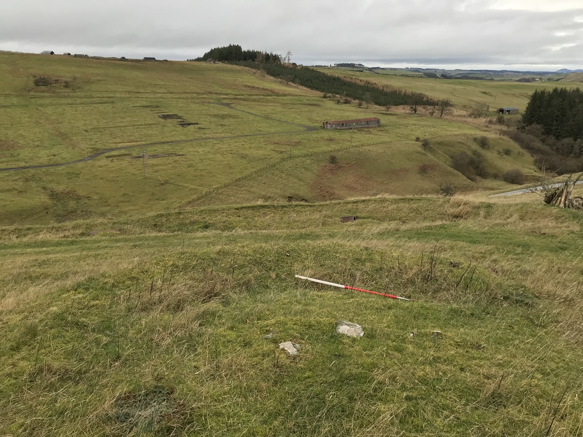 A view across isolated moorland towards a surviving hut from a military camp