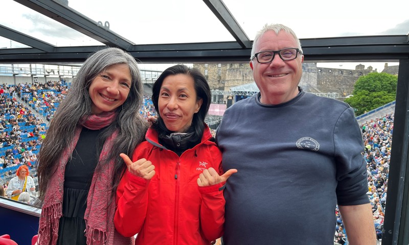 Our volunteer Joyce at the Lumineers concert at Edinburgh Castle posing with two fellow volunteers