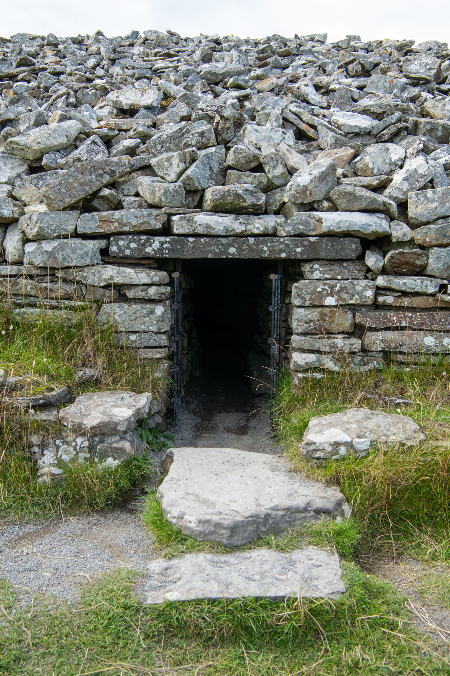 Narrow stone entrance framed by stacked rocks and grassy edges.
