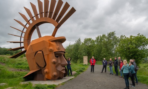 A group of people outside looking at a roman statue