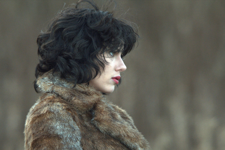 Side profile of a woman with black curly hair and wearing a fluffy coat