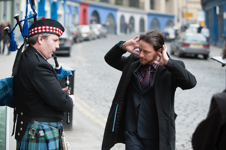 Detective Sergeant Bruce Robertson (James McAvoy) in Filth putting his fingers in his ears beside a bagpipe player on an Edinburgh street