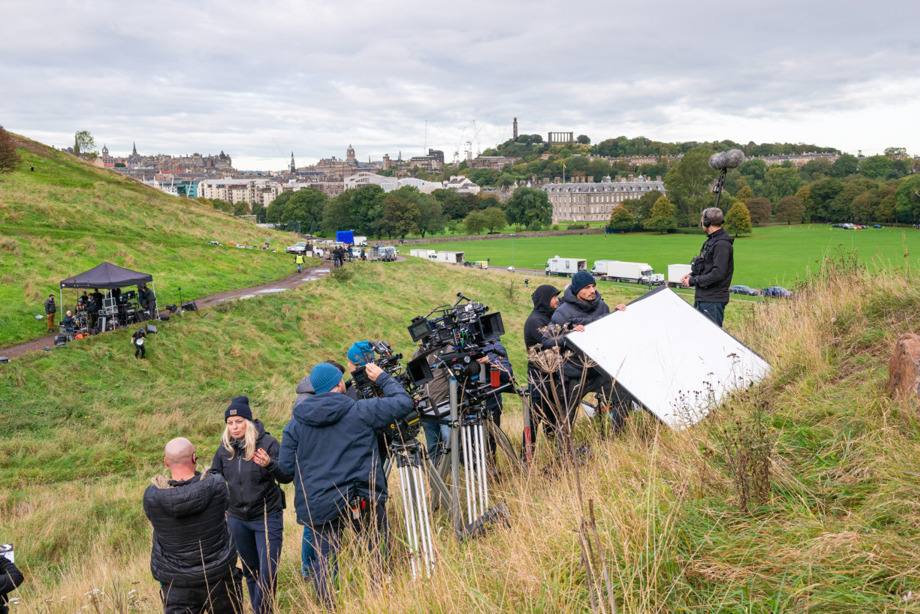 Filming taking place on the grounds of Arthur's Seat with Holyrood Palace in the background