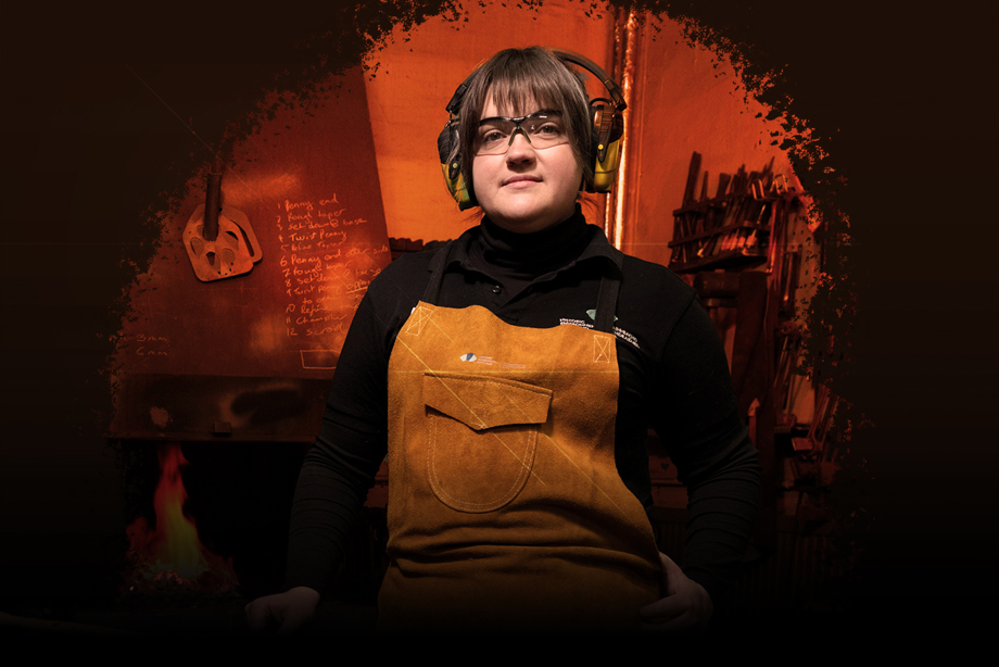 A woman wearing HES branded bib and brace overalls, protective glasses and ear defenders