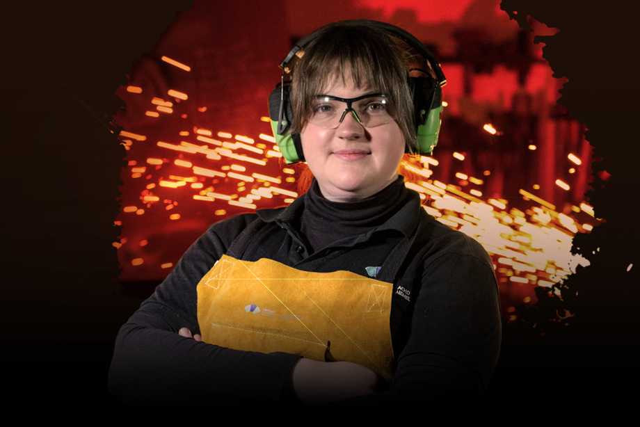 A woman wearing HES branded bib and brace overalls, protective glasses and ear defenders