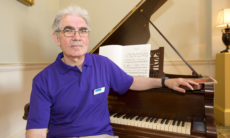 A volunteer sitting by a piano