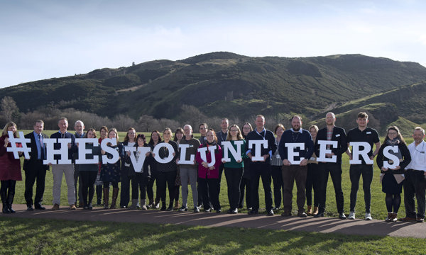 Volunteers holding up letters to spell out HES Volunteers