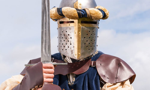 A re-enactor wearing a knight’s armour and holding a sword.