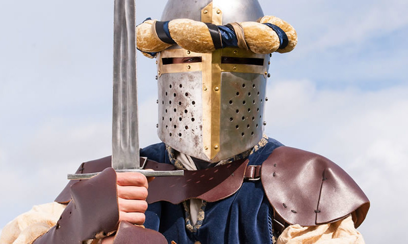 A re-enactor wearing a knight’s armour and holding a sword.