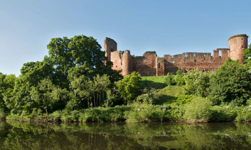 An exterior view of Bothwell Castle, nestled among trees on the River Clyde.
