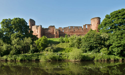 An exterior view of Bothwell Castle, nestled among trees on the River Clyde.