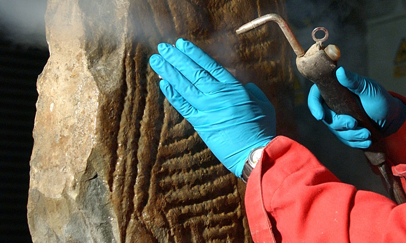 A staff member cleaning a carved stone.