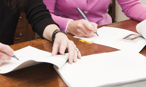 Two people shown signing documents.