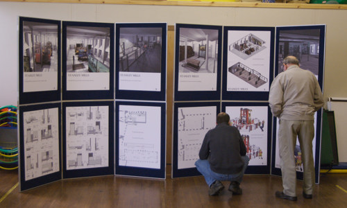 Two members of the public examining information panels for a consultation.