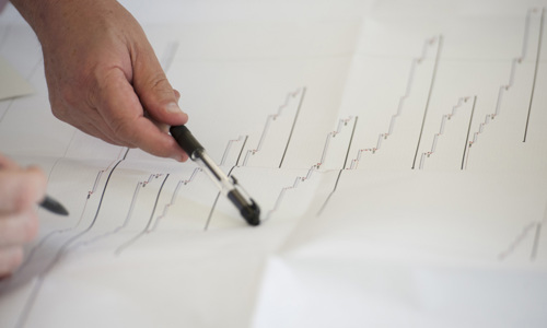A person uses a pen to point to a printout of a graph.