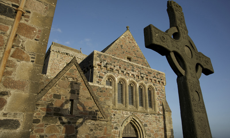 A view of St John’s Cross casting a shadow on the wall of Iona Abbey.