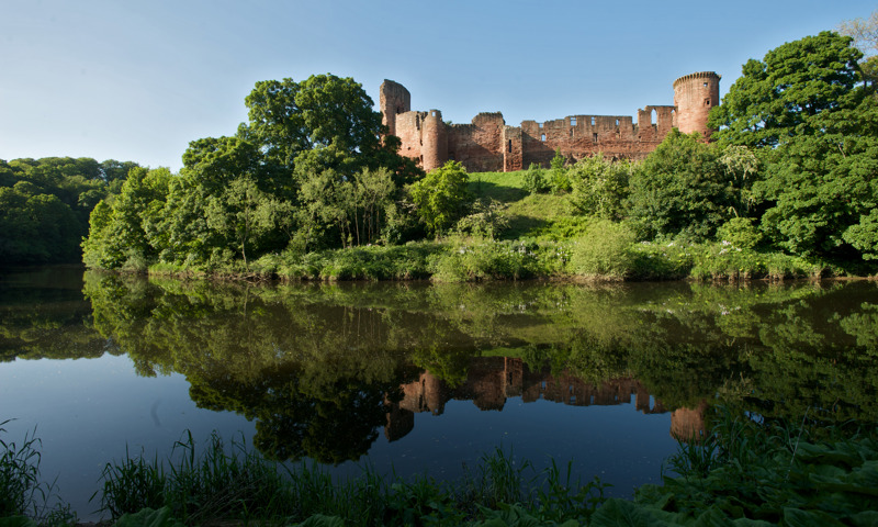 A general view of Bothwell Castle, among trees on the River Clyde.
