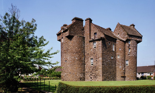 The red stoned Claypotts Castle with its striking circular towers and asymetric layout.