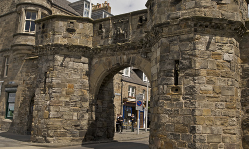 A strong looking tower gate with the saltire flag flying above it