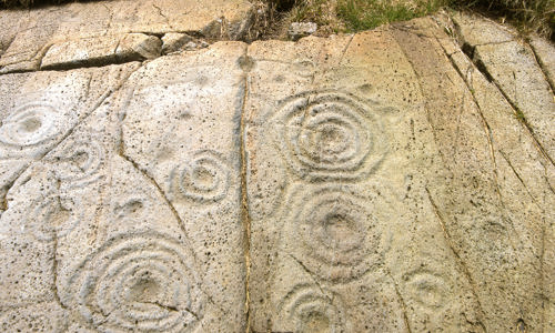 Multiple rings of concentric circles are carved into the smooth rock.