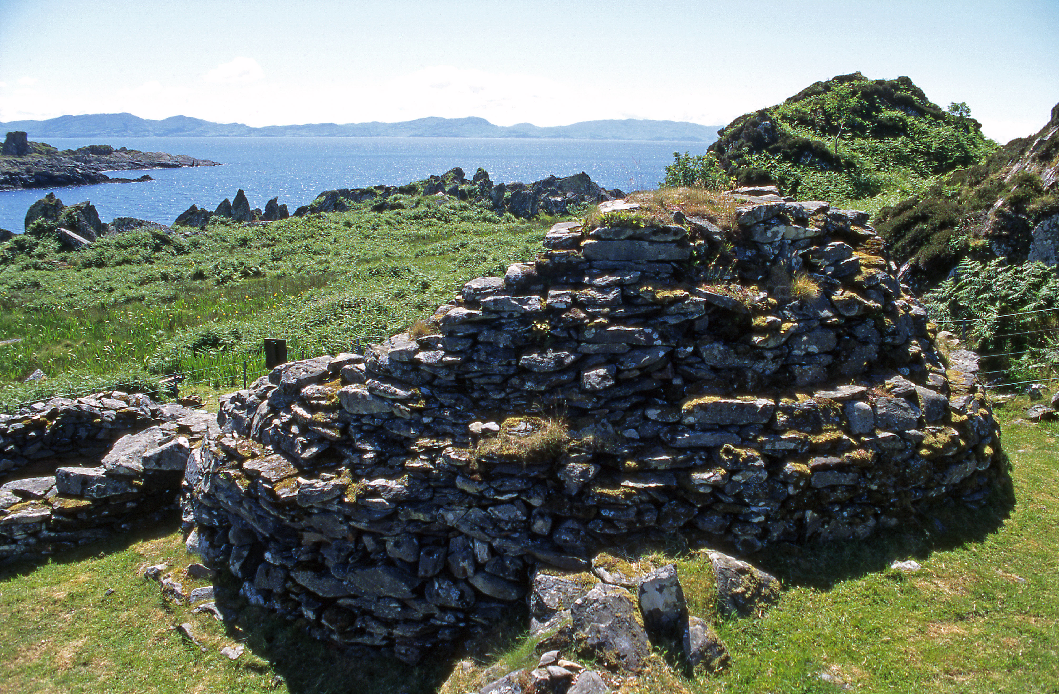 The ruins of Eileach an Naoimh with cliffs and the sea in the background.