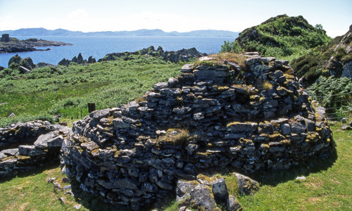 The ruins of Eileach an Naoimh with cliffs and the sea in the background.