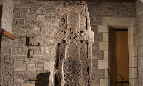 A tall cross-slab with Pictish symbols in a small hall in the Parish church.