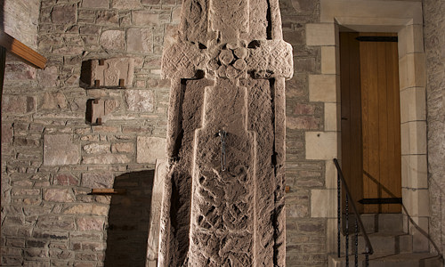 A tall cross-slab with Pictish symbols in a small hall in the Parish church.