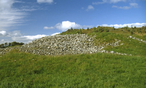 A grassy landscape with the remains of a stone wall that could be mistaken for a small quarry