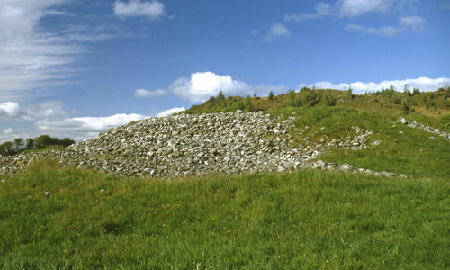 A grassy landscape with the remains of a stone wall that could be mistaken for a small quarry