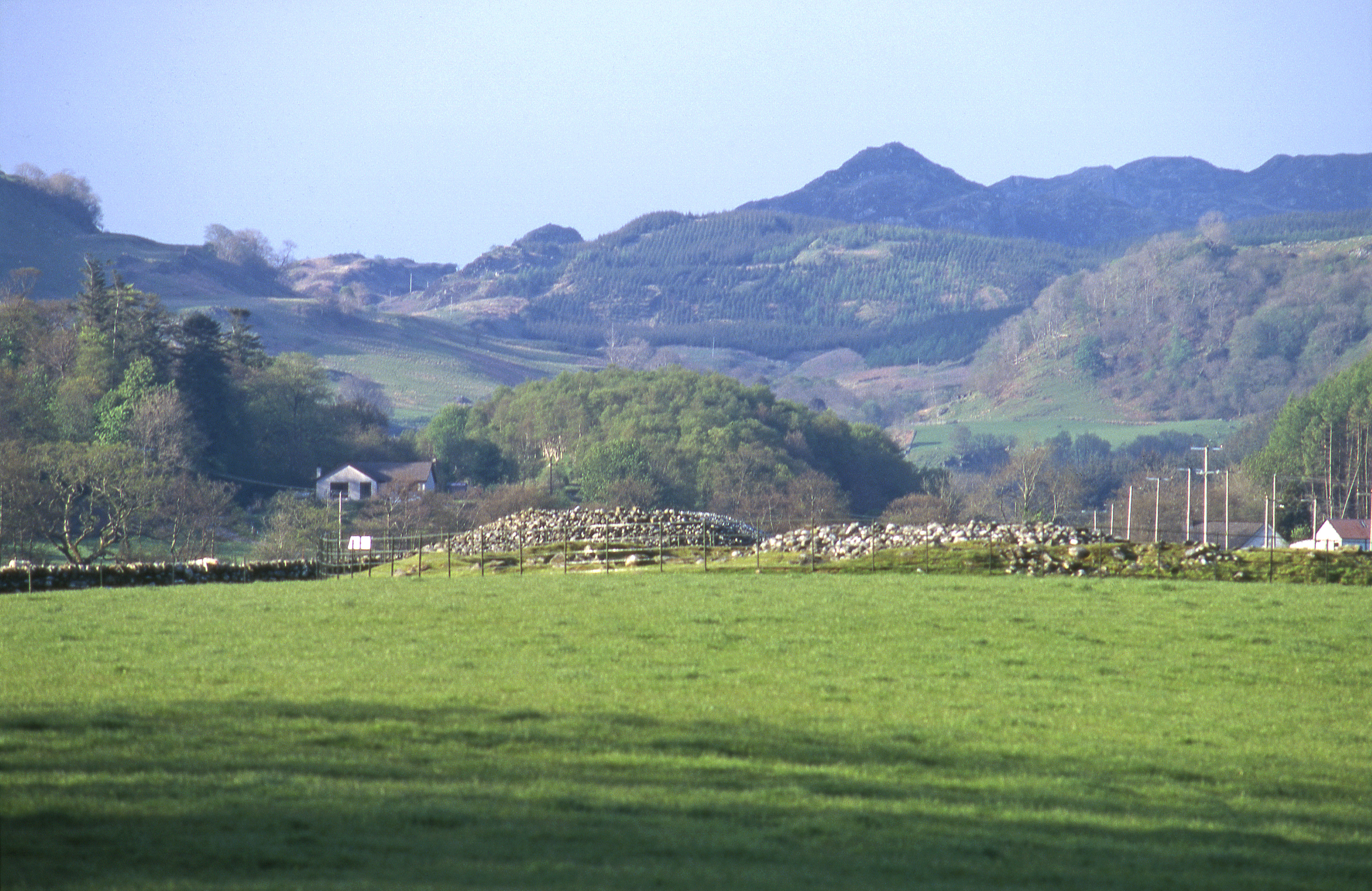 Two low cairns with hills and forest behind it.