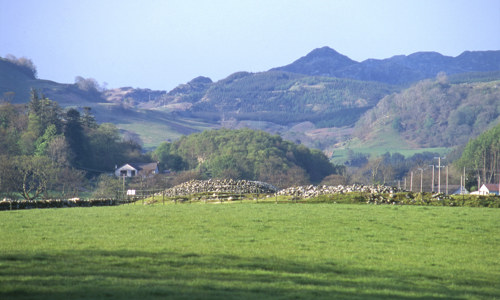 Two low cairns with hills and forest behind it.