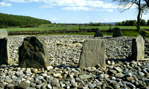 Several low standing stones in a circle, surrounded by pebbles.
